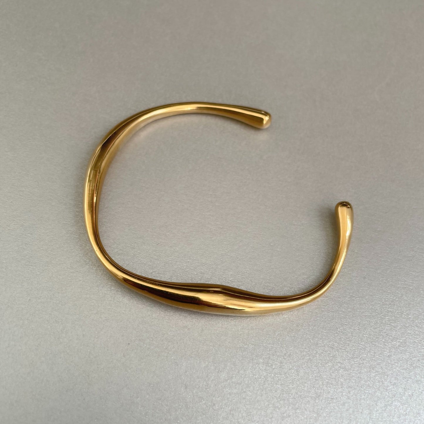 Danai Luxe 18k gold plated irregular shaped bangle bracelet on gray background